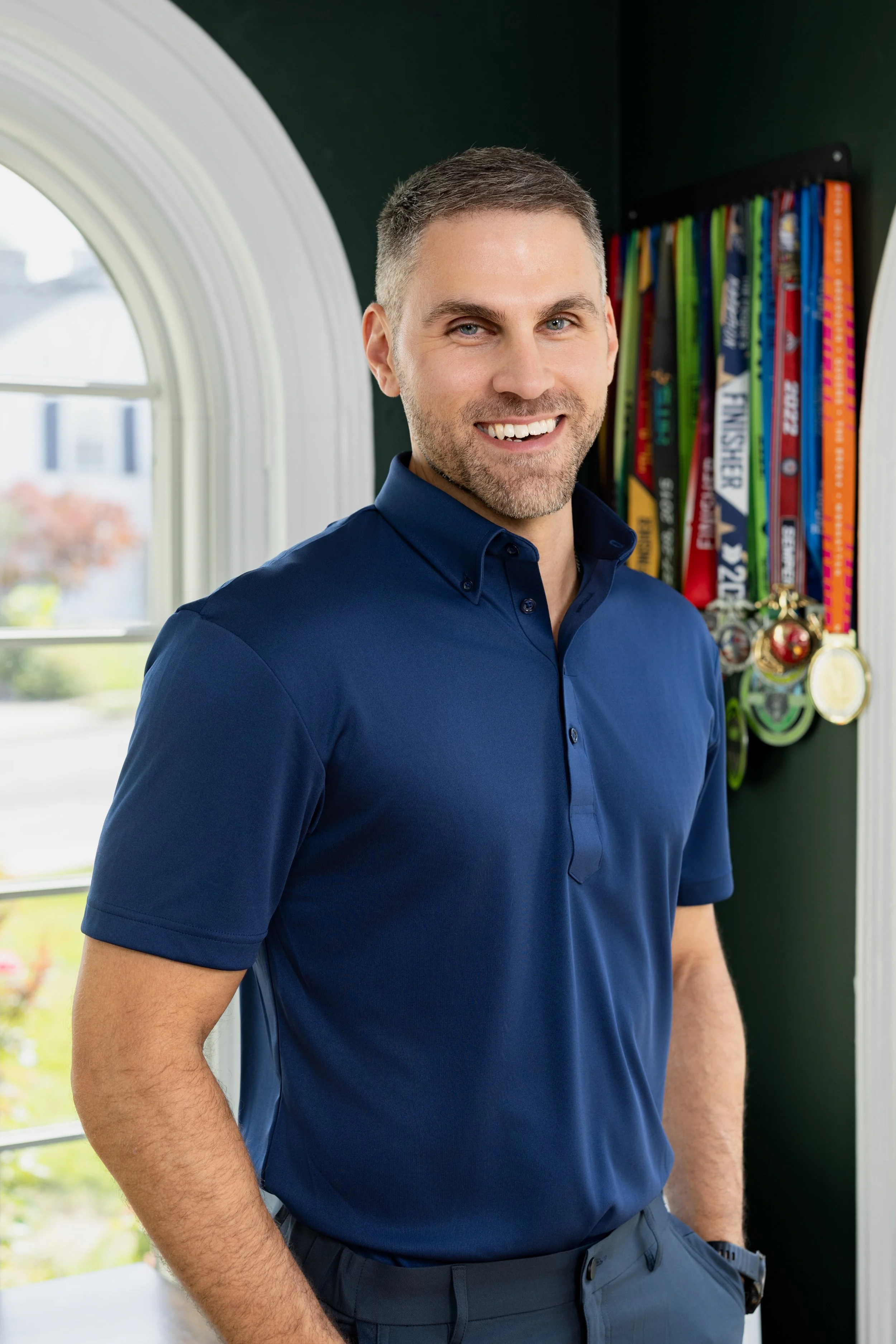 Portrait of a man in a blue polo shirt in his office smiling