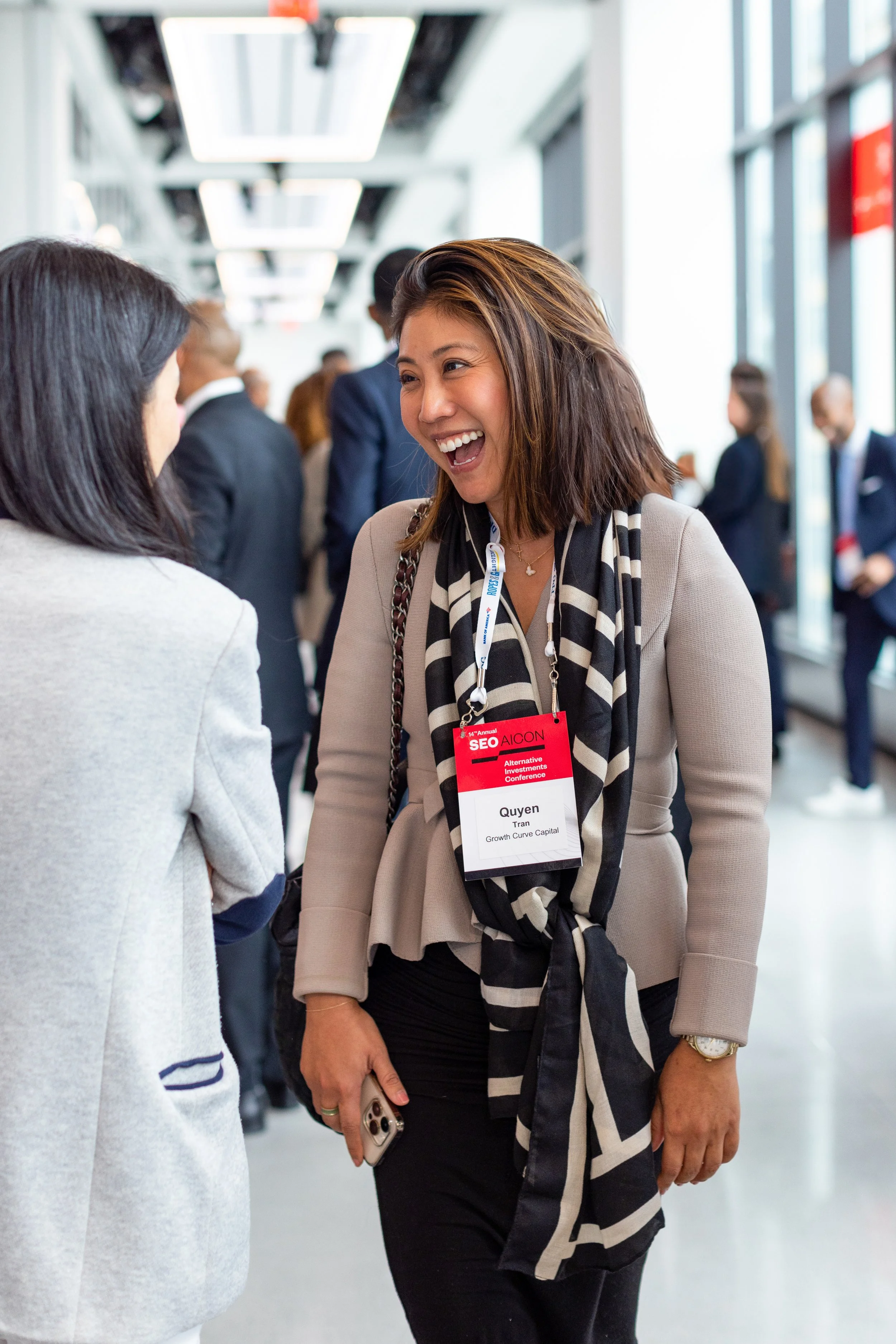 A woman with a sweater and brown hair smiling at another conference attendee 