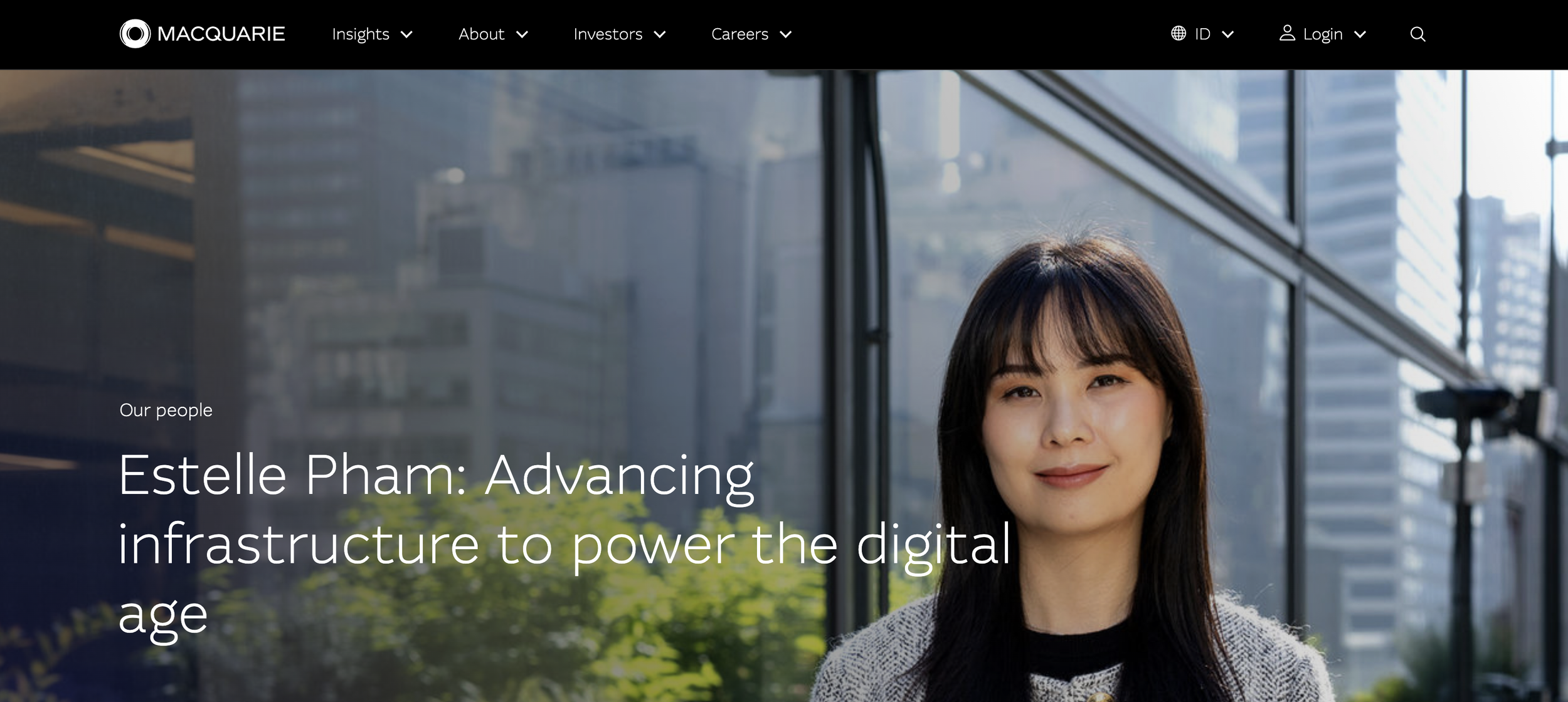 A woman with black hair in front of the outside of her office building smiling at the camera