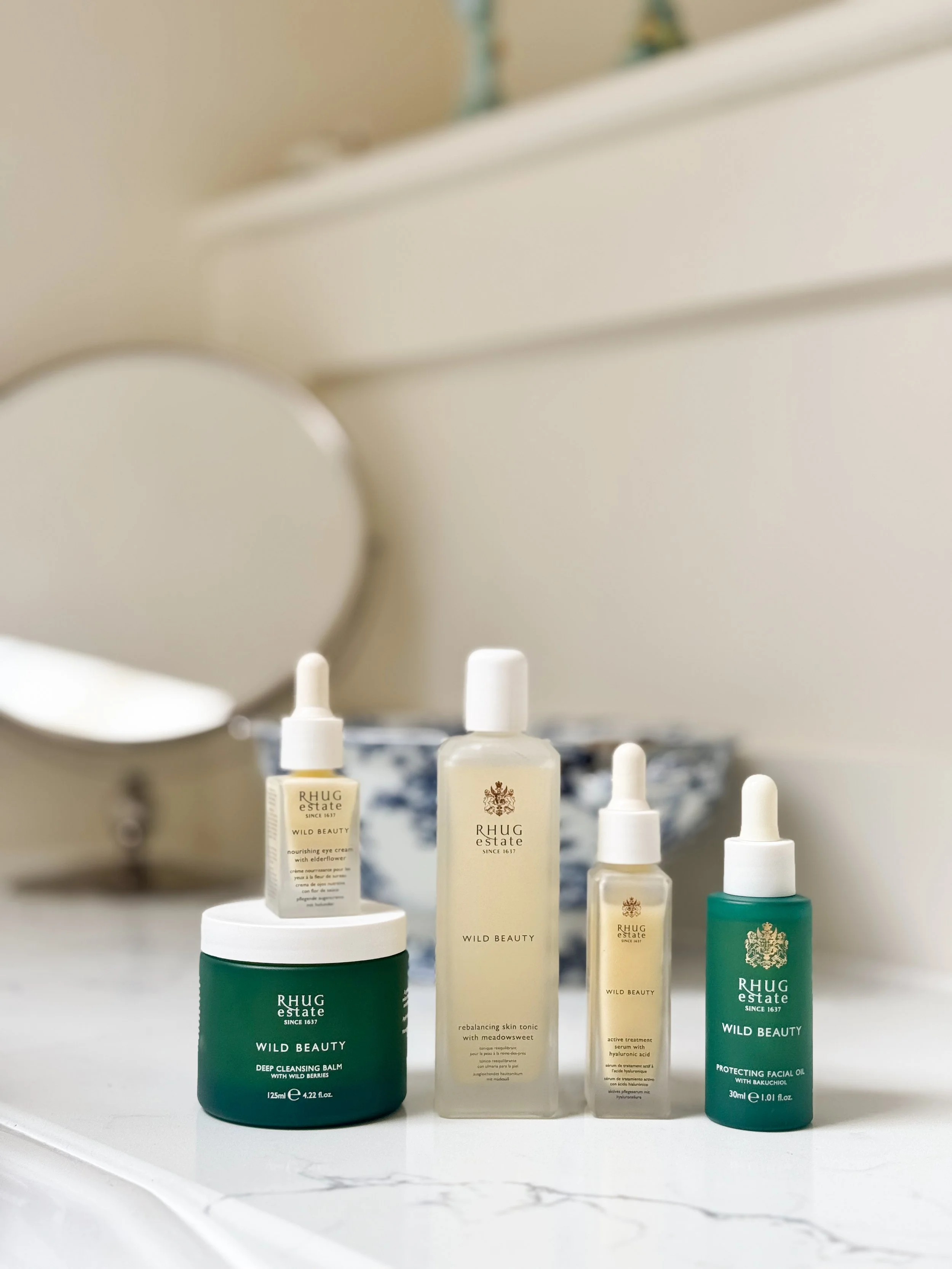 Display of skincare products on a bathroom or vanity surface, including bottles and jars from Rhug Estate's Wild Beauty line.