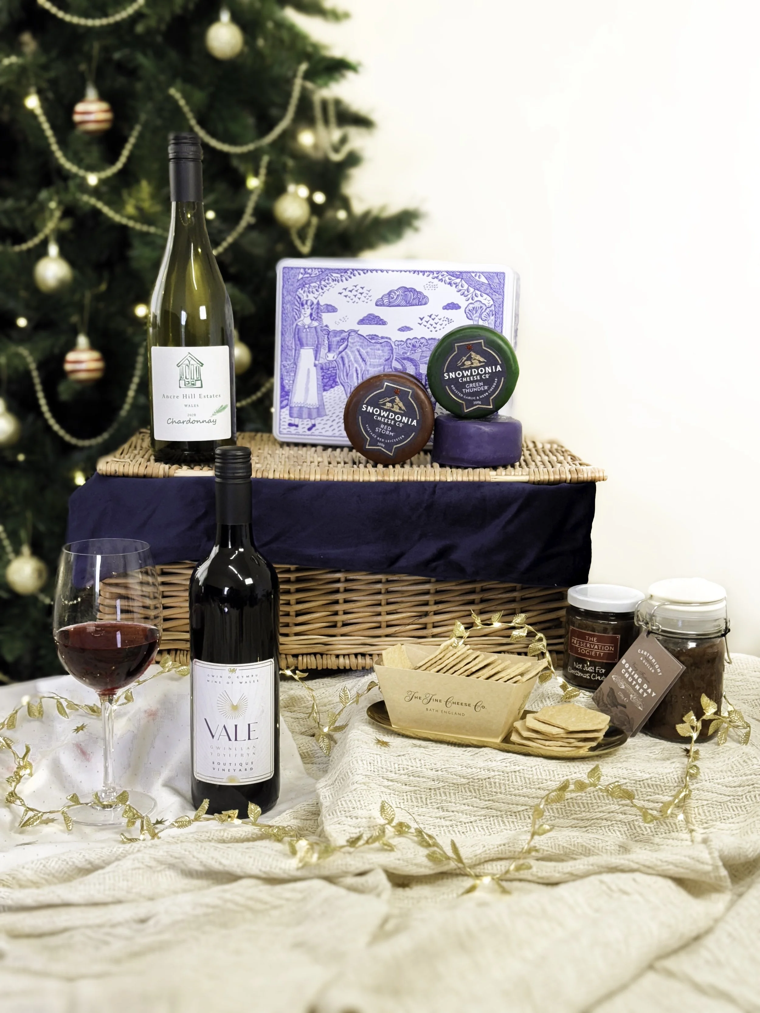 Wedding or holiday table setting with wine, cheese, crackers, and festive decorations, including a Christmas tree in the background.