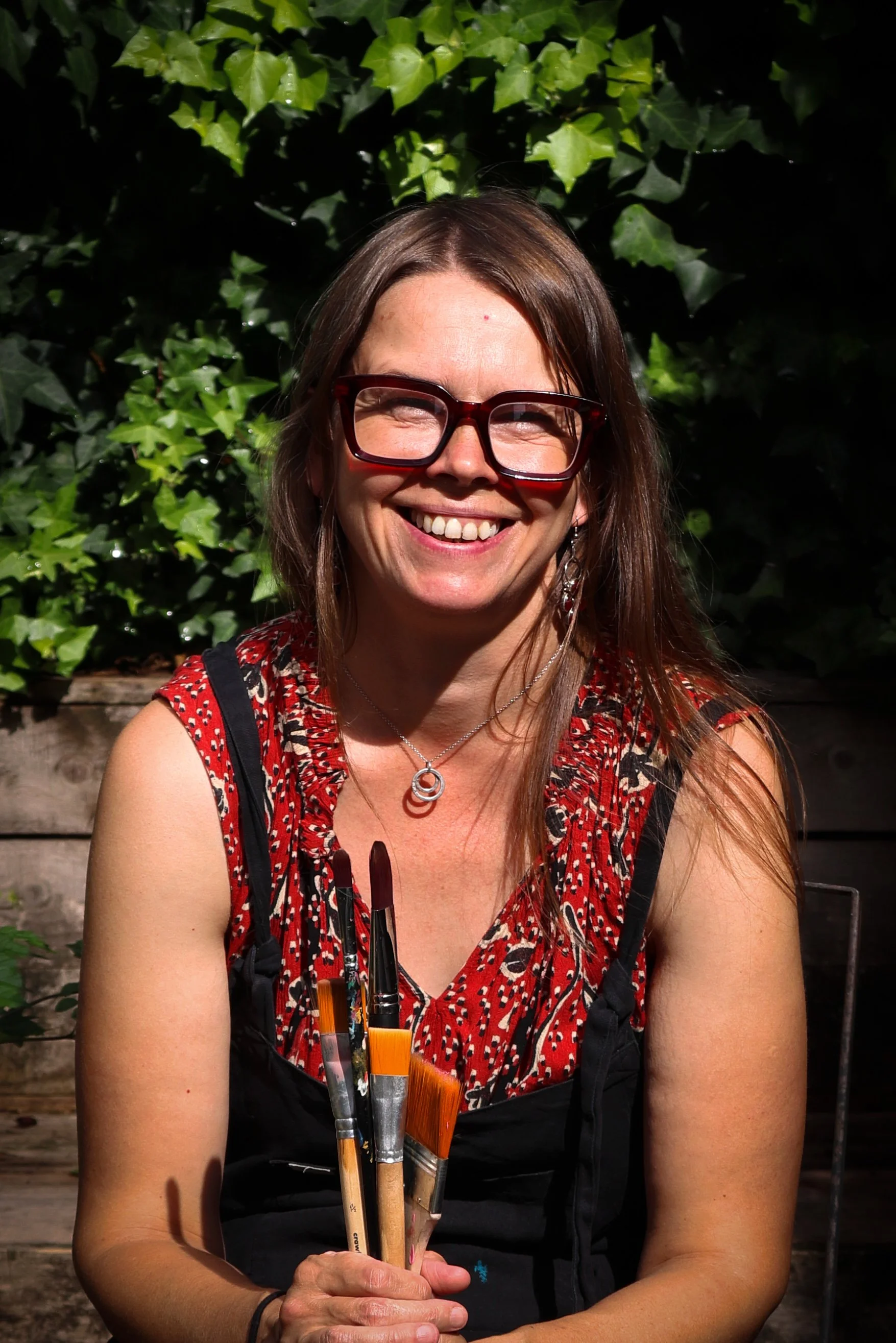 Rachel smiling holding paint brushes