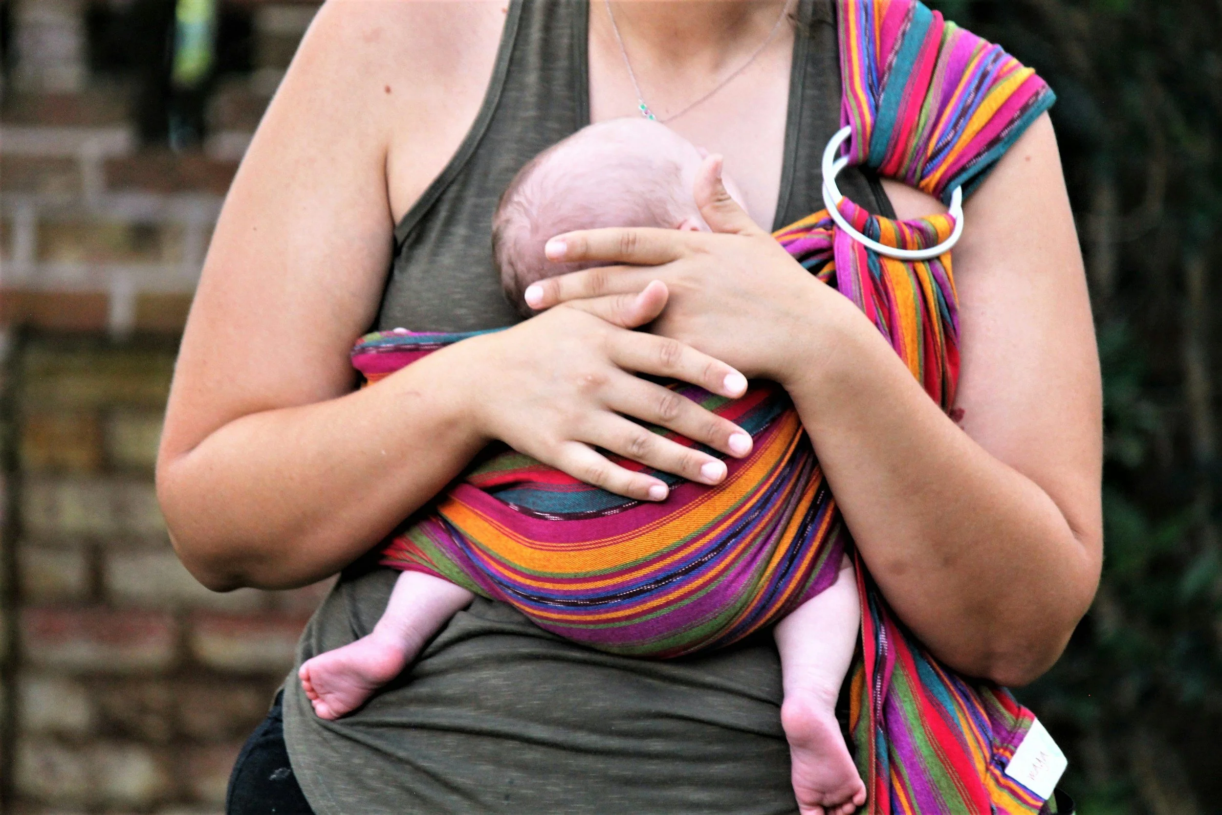 New mother holding infant in baby carrier 