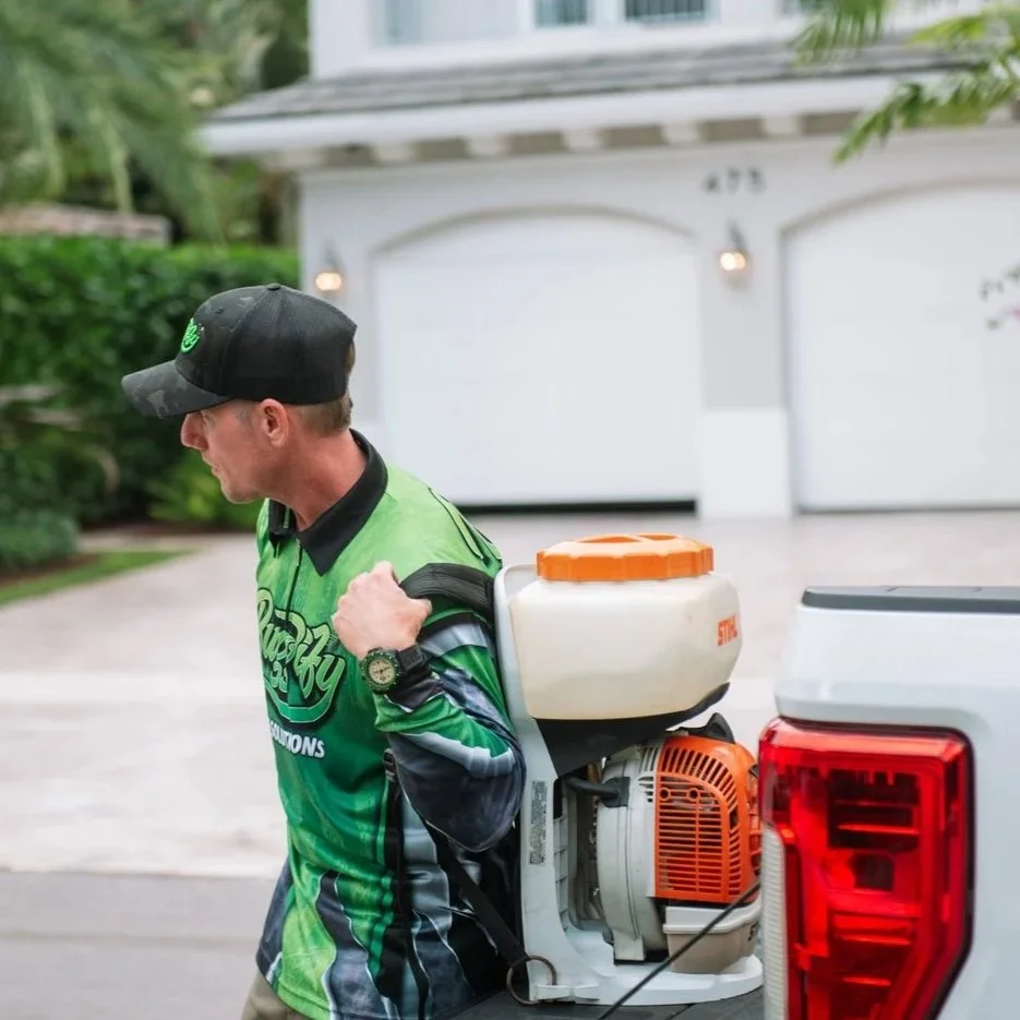 Pest control technician treating residential property in Boca Raton while inspecting bee and wasp activity around South Florida home exterior.