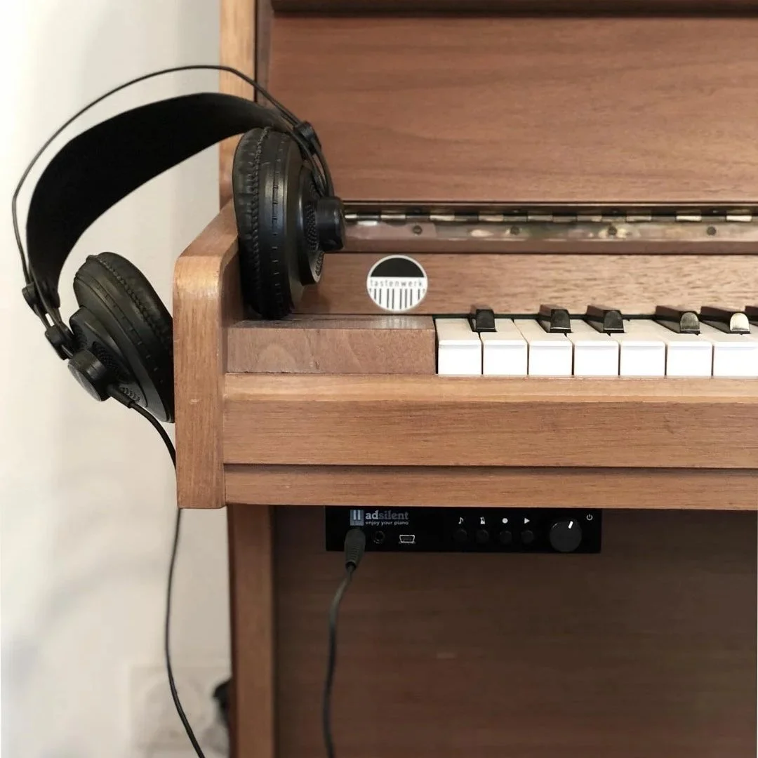 Holzpiano mit schwarzen Kopfhörern auf der Klaviatur.