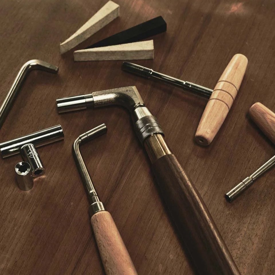 Verschiedene Handwerkswerkzeuge, darunter ein Hammer, Wurzeln, Schraubenschlüssel und andere Werkzeuge, auf einem Holztisch.