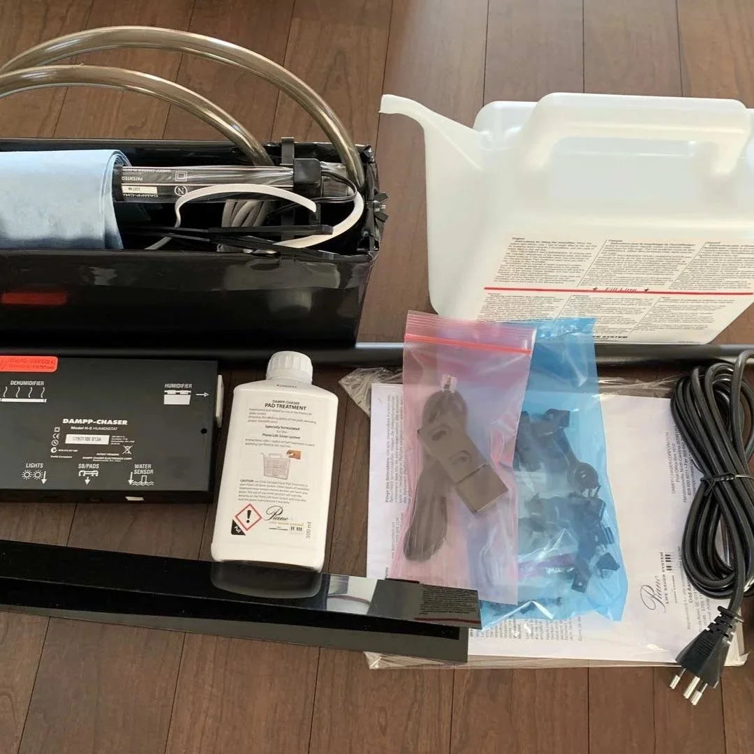 Luftbefeuchterbausatz mit Wasserbehälter, Kabel, Bedienungsanleitung, Desinfektionsmittel, Zubehör und technischen Teilen auf Holztisch.