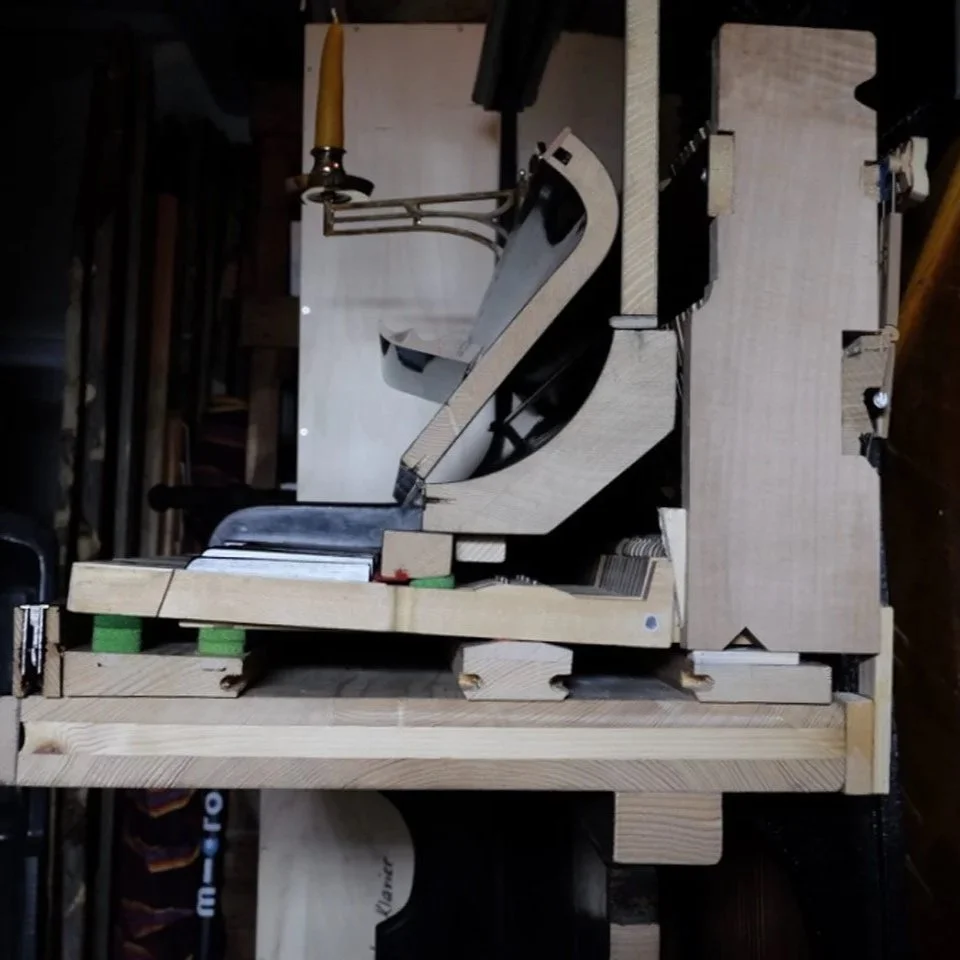 Holzmodell oder Prototyp mit komplexen mechanischen Komponenten, wahrscheinlich ein Konstruktions- oder Maschinenmodell, auf einer Werkbank in einer Werkstatt