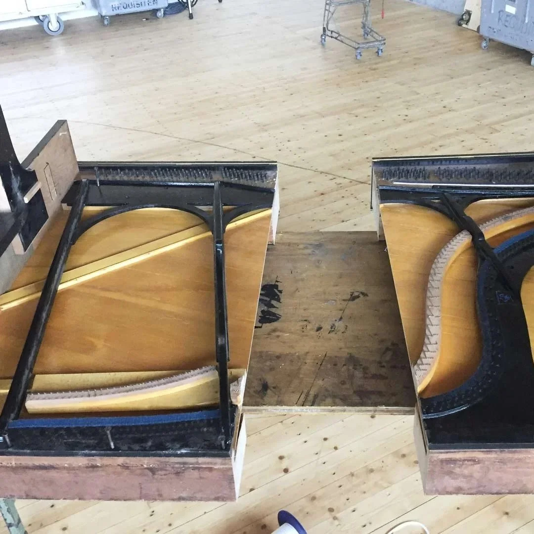 Zwei alte Sesselsitze mit Holzschlägern und Metallrahmen, die auf Holztellern mit dunklem Boden stehen.