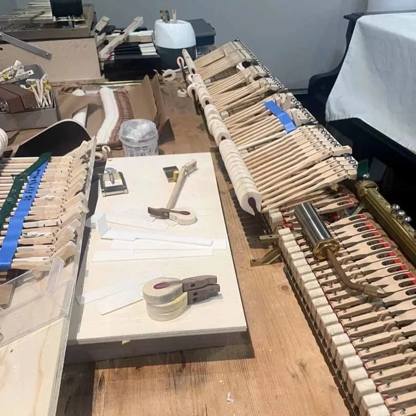 Ein Werkbank mit verschiedenen Klaviersaiten und Werkzeugen für die Reparatur oder das Bau eines Klaviers