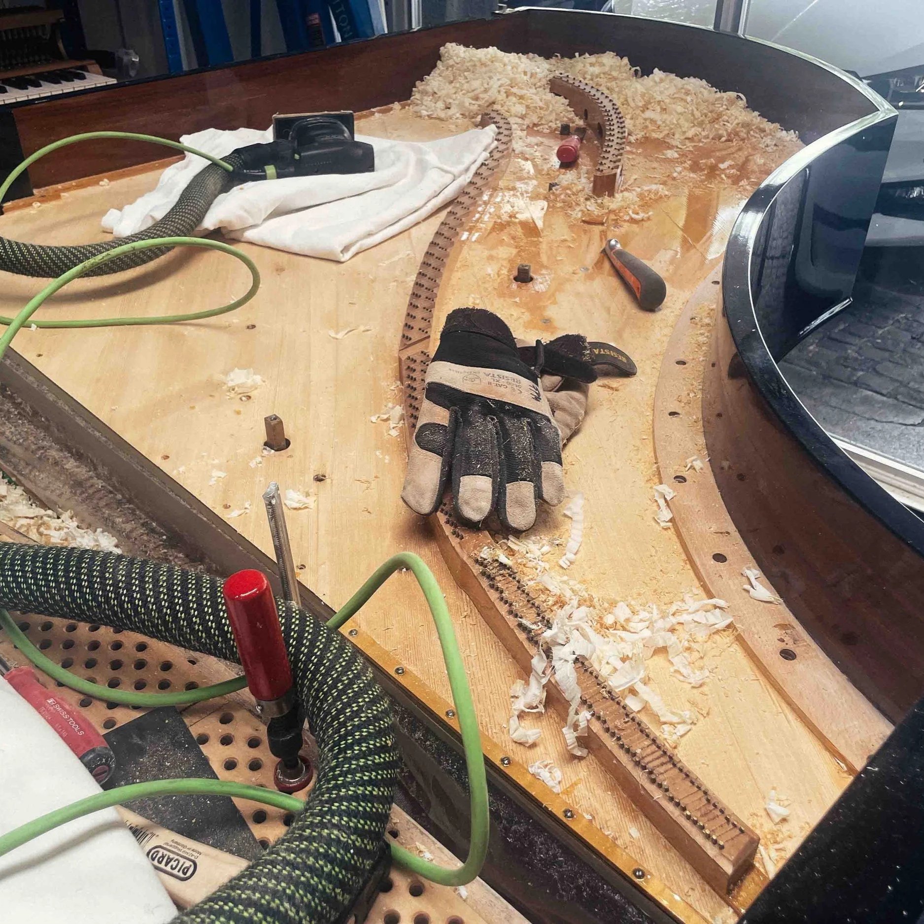 Ein Modell eines Gleisabschnitts, der von Hand gebaut wird, mit Werkzeugen, Schleifpapier, Schmutz und Pappstreifen auf einer Holzplatte, und einer Person, die an dem Projekt arbeitet.