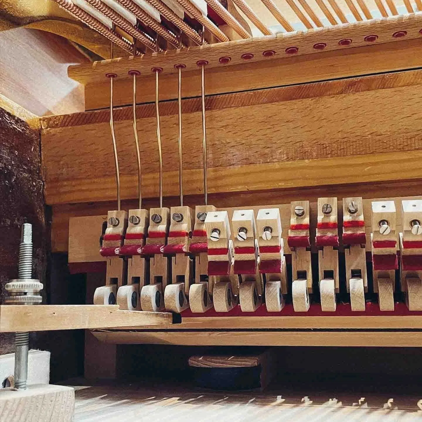 Innenansicht eines Piano-Mechanikteils mit hölzernen und metallischen Komponenten.