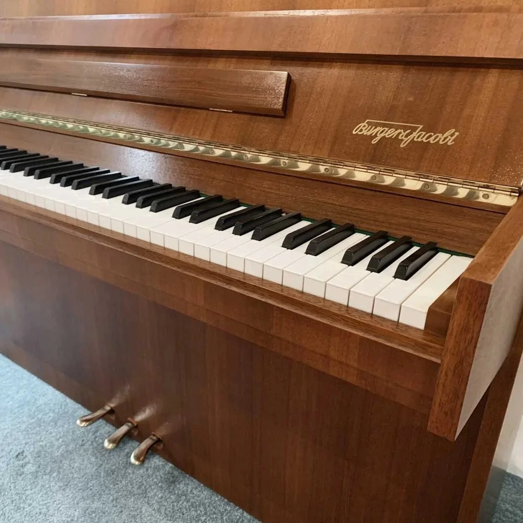 Ein Holzklavier mit schwarzen und weißen Tasten und den Pedalen am Boden.