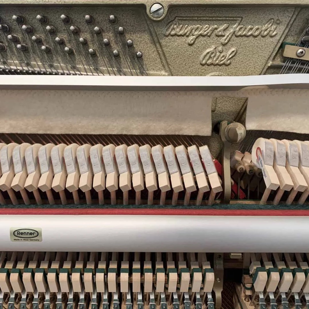 Innenansicht eines Klaviers mit sichtbaren Saiten, Hämmerchen und Mechanik. Das Markenlogo 'Renner' ist sichtbar.