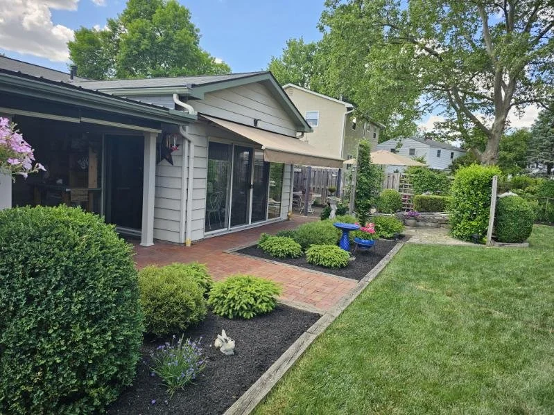 Front of house garden beds with manicured lawn and shrubs by Final Touch Lawn Care