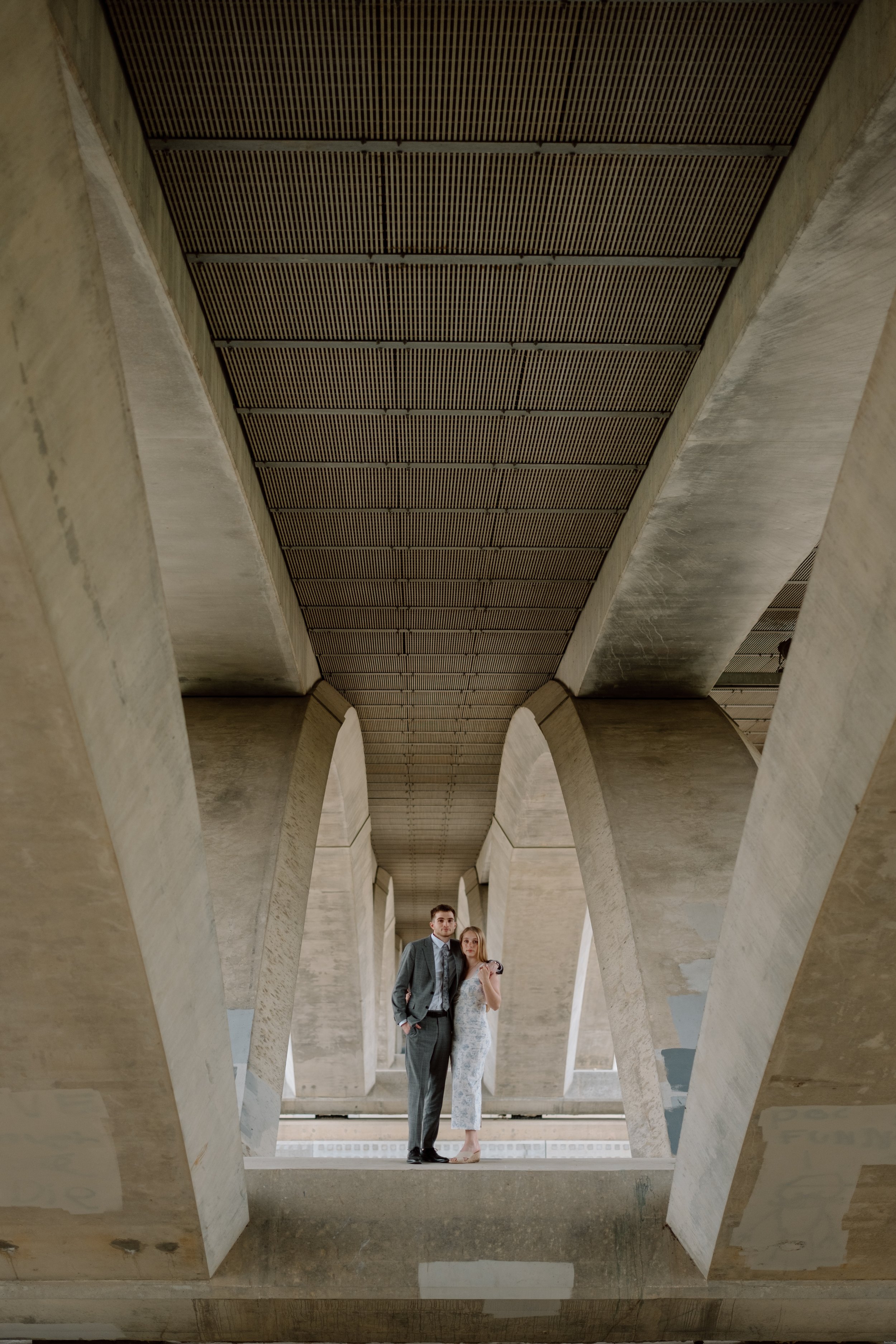 A man and woman in formal attire standing under a large concrete structure with arches in Columbus, Ohio.