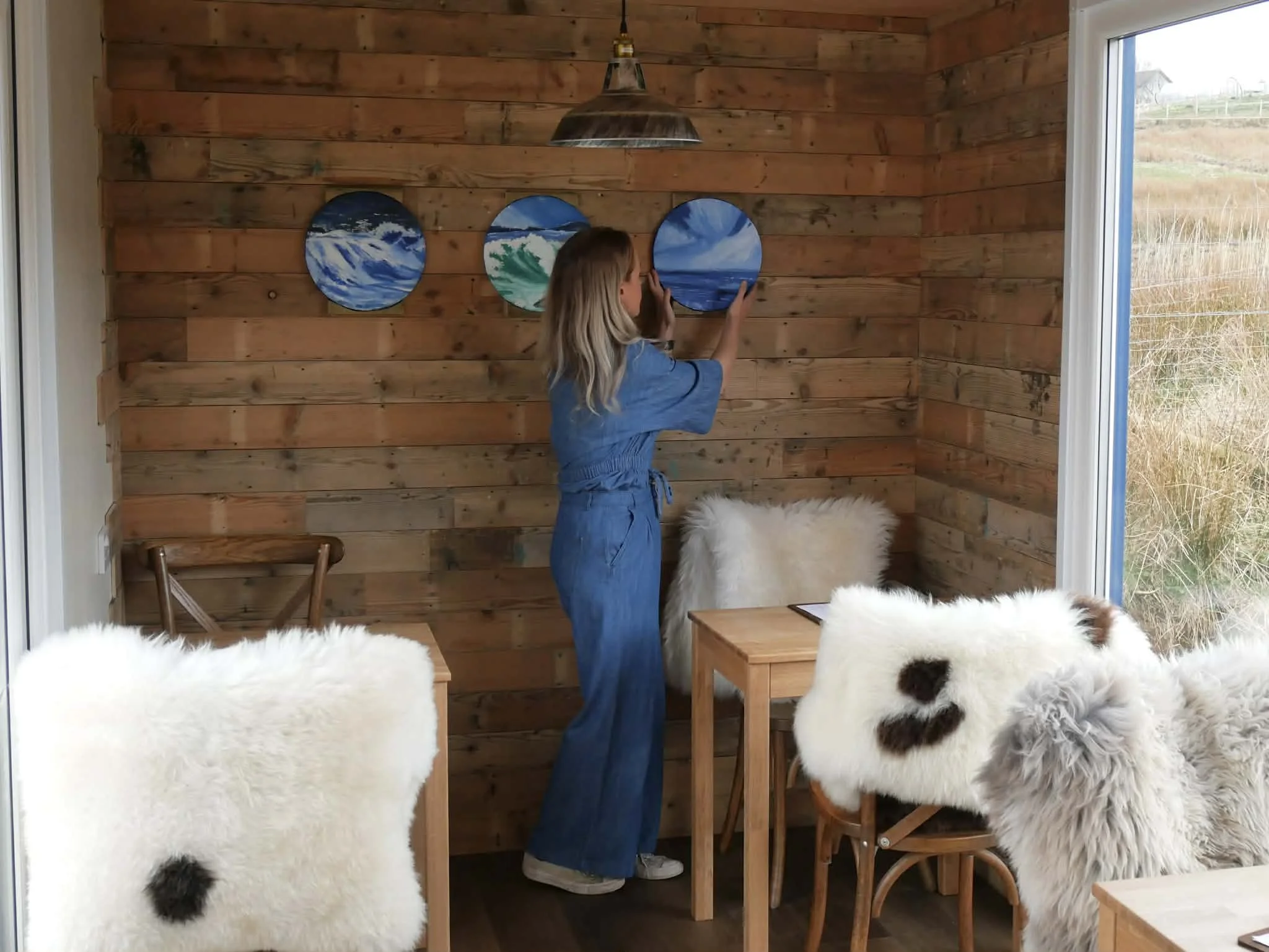 Heather Mercer hanging porthole artwork by Scourie artist Sheilah Cunningham inside Crofter's Kitchen's new container restaurant, Scourie, NC500.