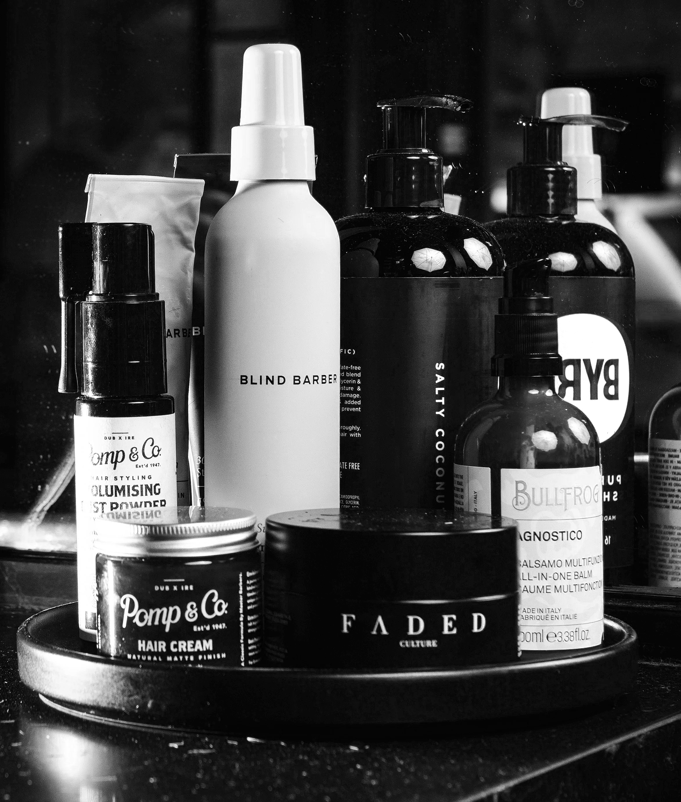 A collection of hair and skincare products on a round tray, including bottles and jars with various labels and packaging.