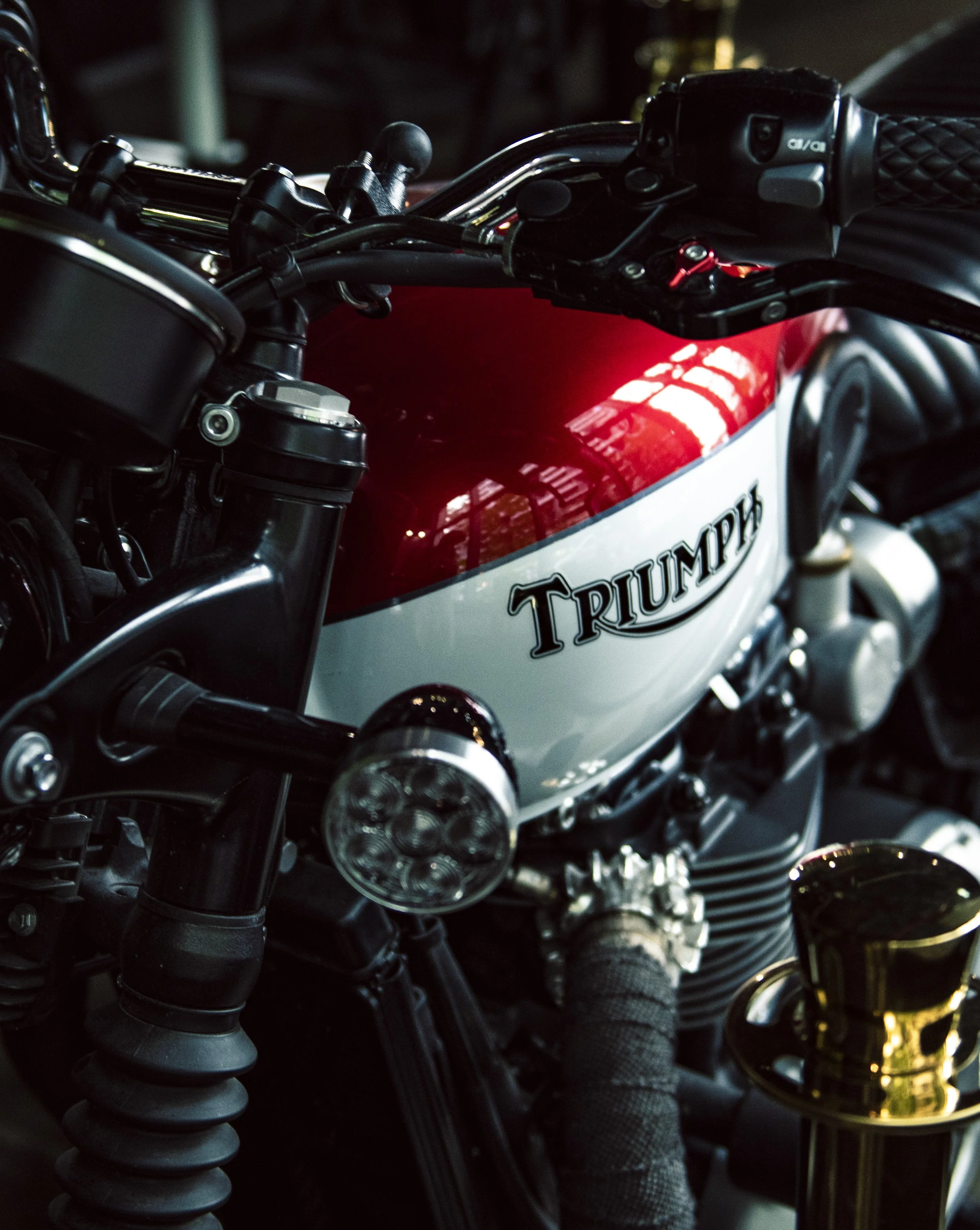 Close-up of a motorcycle's handlebar area at night, showing the throttle grip, front suspension, and part of the fuel tank with a 