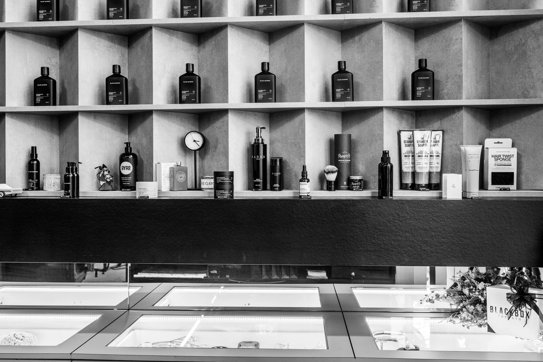Store display shelves with hair care products, a clock, and a flower arrangement.