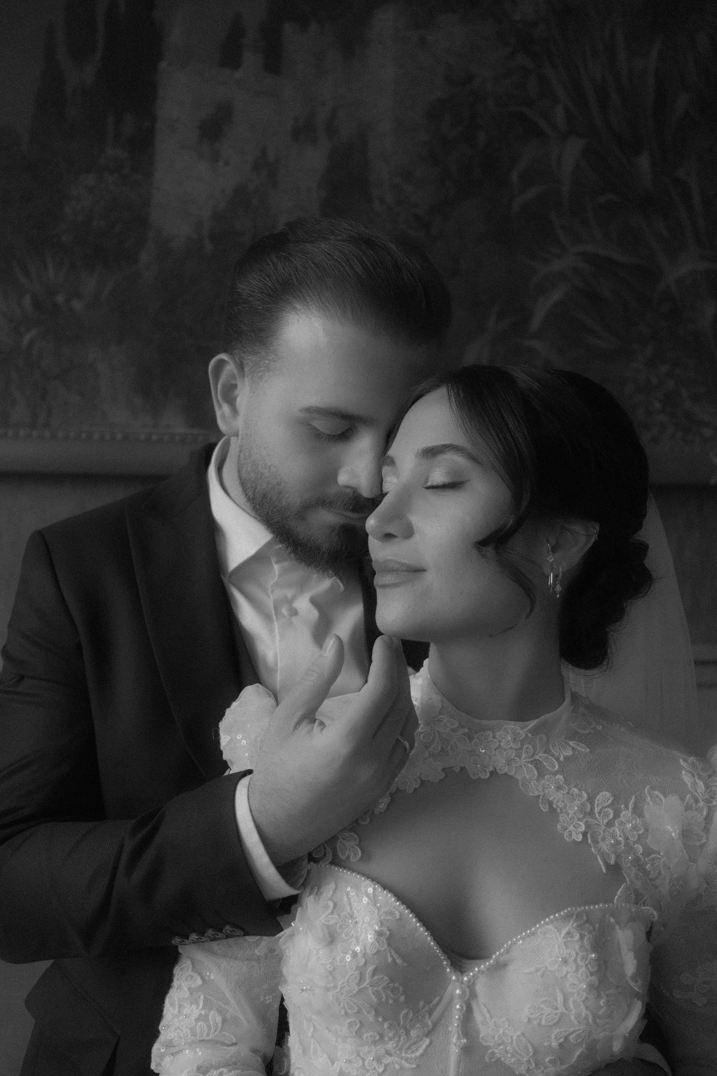 Et ungt par og jente i bergen på bryllupsfeiring, begge har solbriller med hjerteform og skriver 'S+1' og datoen 15.06.24. De smiler og sitter ved bord med blomster, lys og drikke.