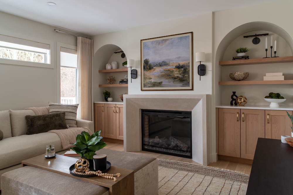 Modern living room with a white sofa, concrete fireplace, and built-in shelves with decor.