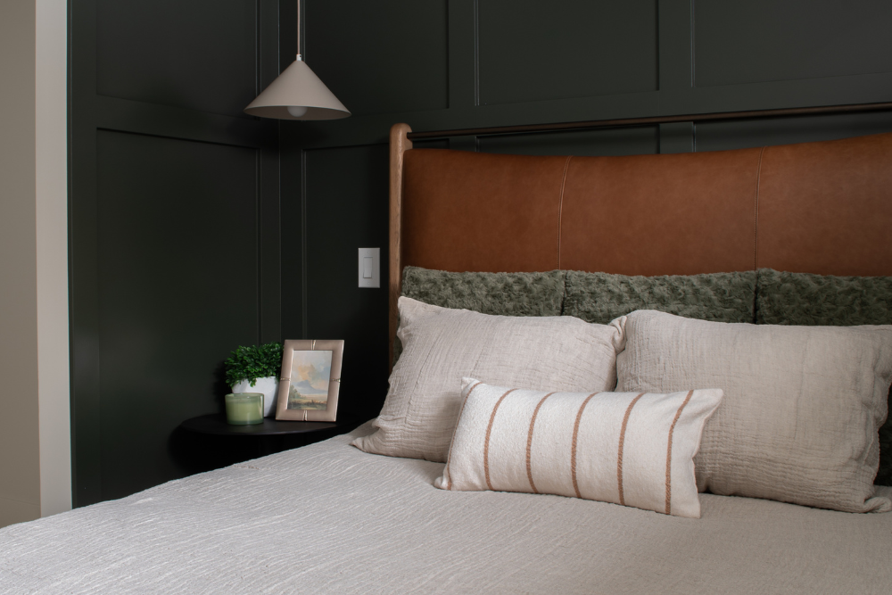Close-up view of layered textured and striped pillows against a leather panel headboard in a master bedroom.