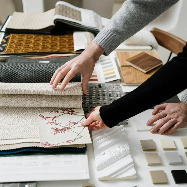 Interior designer reviewing fabric swatches, wallpaper samples, and material finishes — EBO Design, Edmonton interior design studio curating cohesive palettes through a detailed design process.