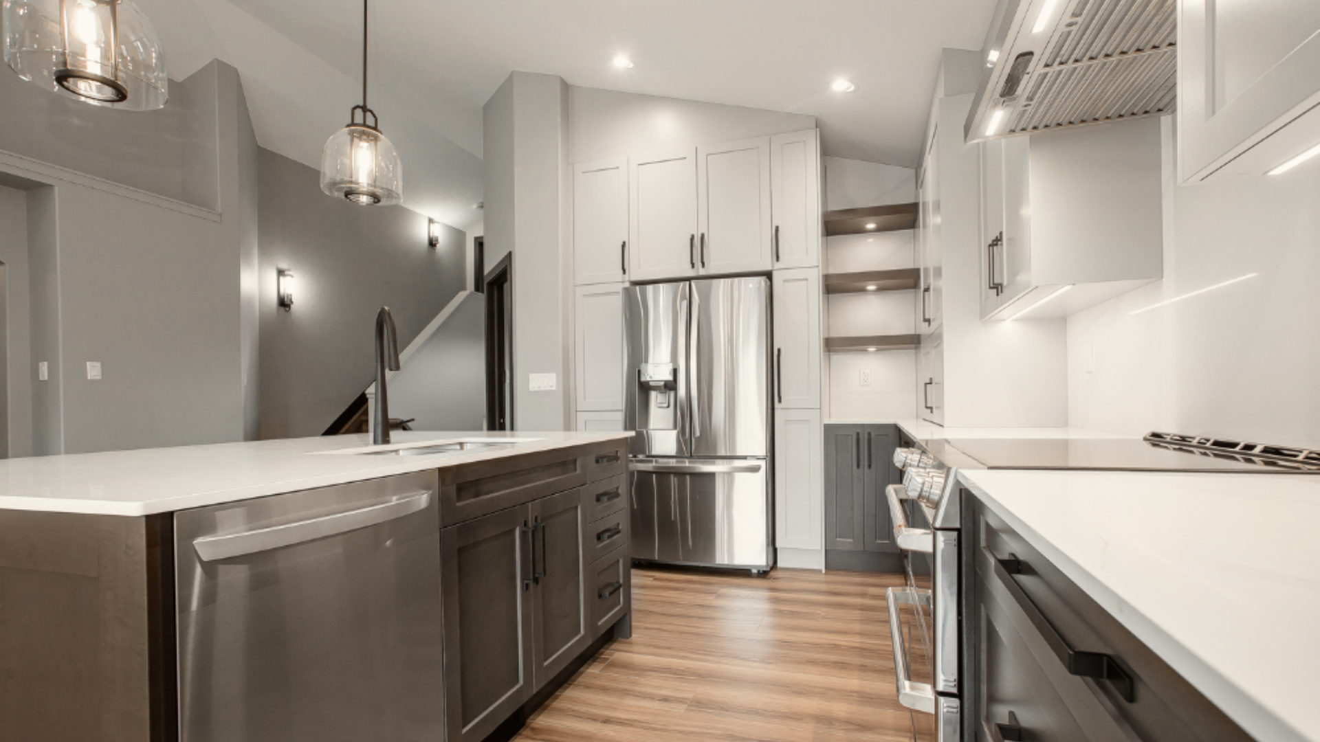 Perspective view of a dark wood kitchen island with a stainless steel dishwasher, white cabinets, and light hardwood flooring.