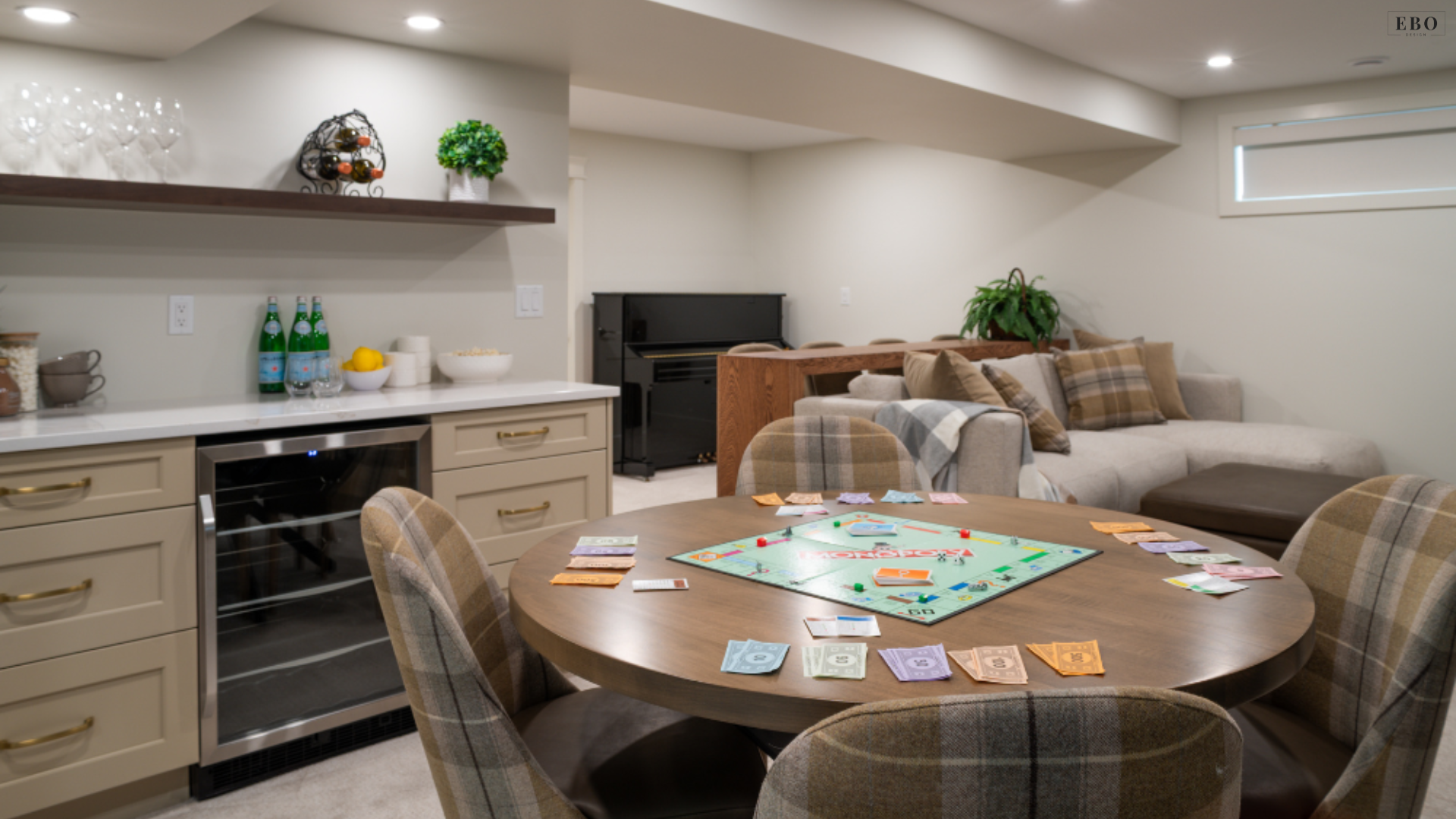 Cozy basement lounge featuring a game table, plush sectional sofa, and built-in wet bar with a wine fridge for family entertainment.