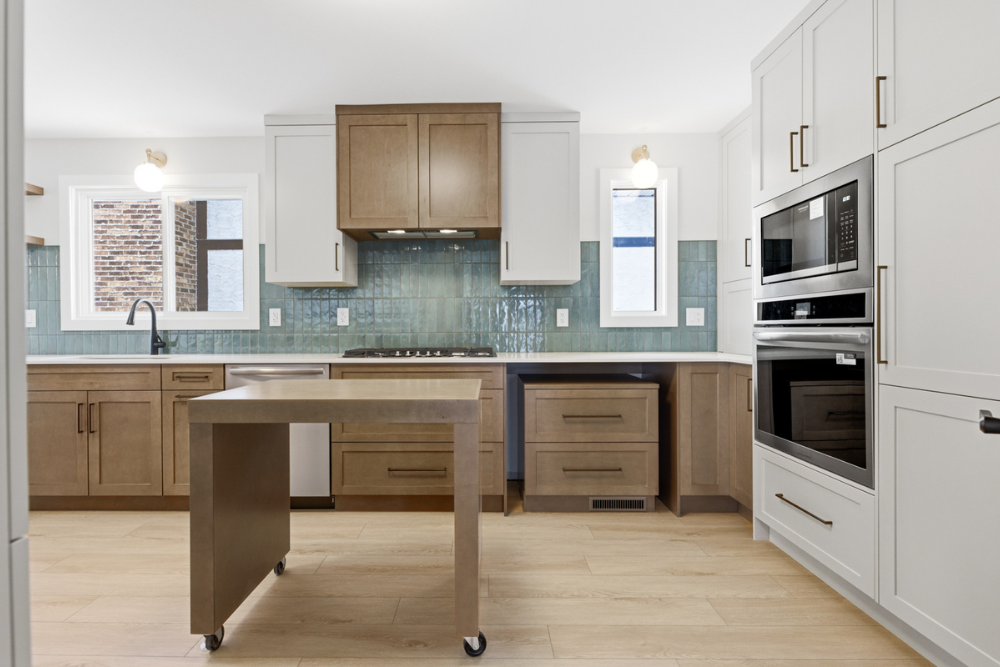 A functional kitchen design showing a mobile wood island on wheels pulled out from the cabinetry to provide additional food preparation space in the center of the room.
