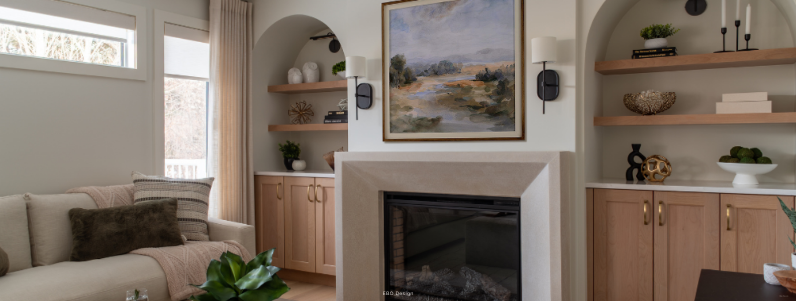 A cozy, modern living room featuring a concrete fireplace, light wood built-in cabinets, and a comfortable sofa.