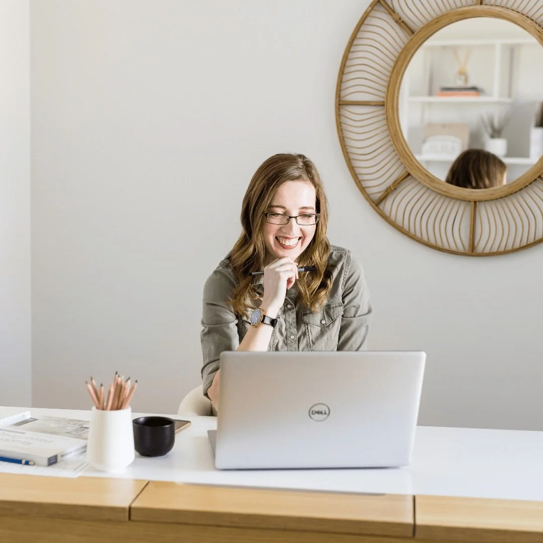 Chelsey Corea, Edmonton interior designer and founder of EBO Design, smiling during a virtual design consultation at her desk.