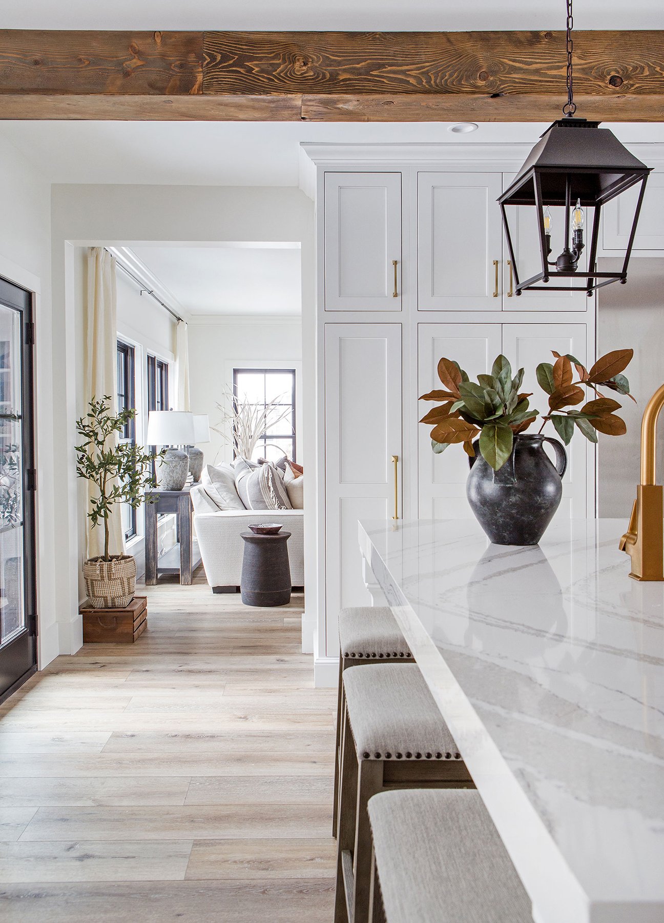 Bright open-concept kitchen and living room with white cabinetry, marble countertop, natural wood accents, and layered decor—showcasing the inviting, cohesive styling created by a professional interior designer.