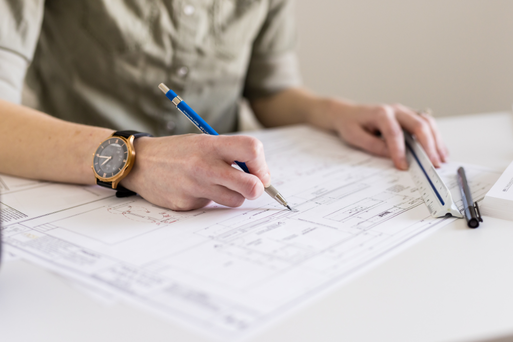 Interior designer reviewing and marking up residential floor plans with scale ruler — EBO Design, Edmonton interior design studio specializing in detailed drawings and home renovation planning.