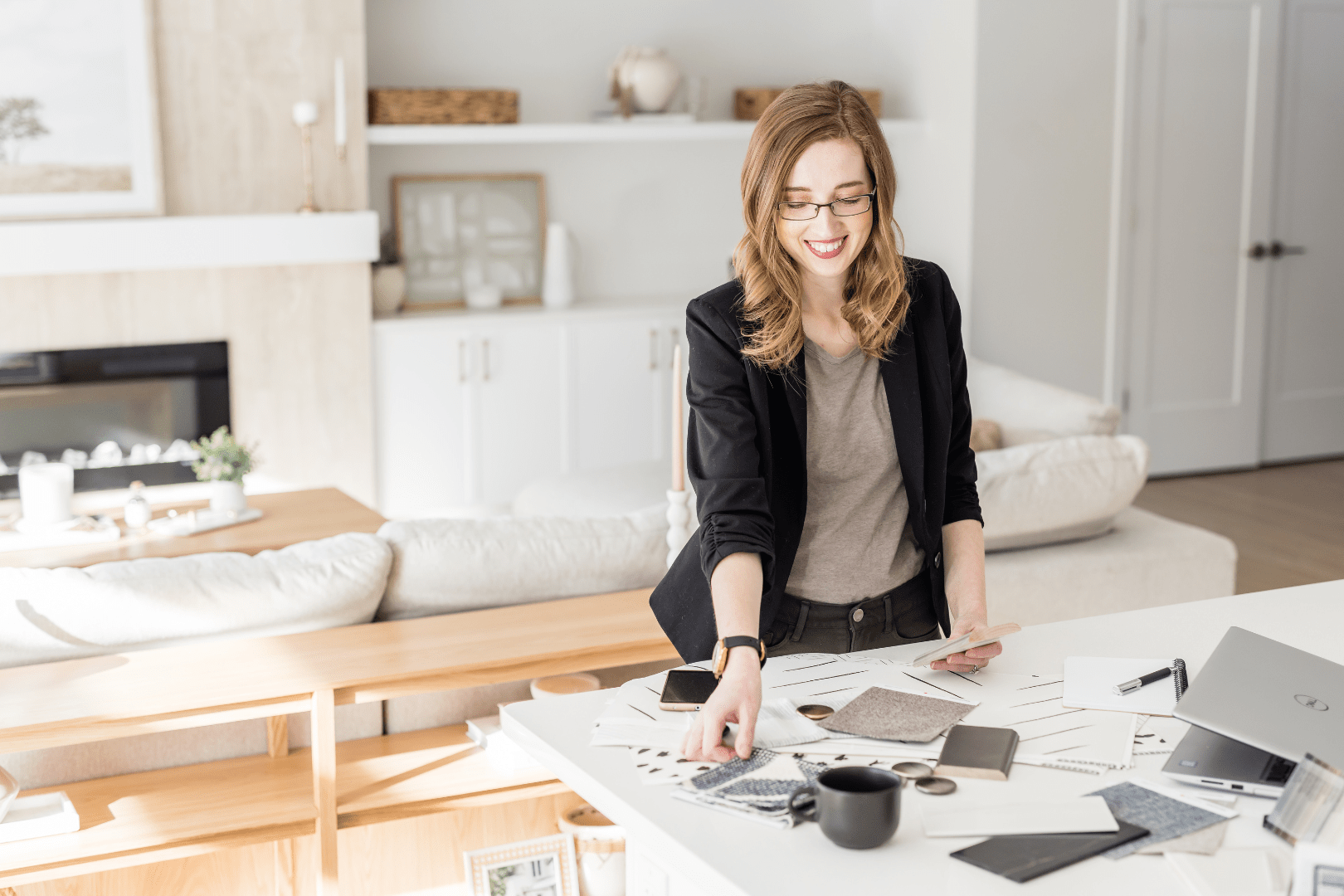 Chelsey Corea, Edmonton interior designer and founder of EBO Design, reviewing material samples and finishes during the design development process in a modern, neutral living room.