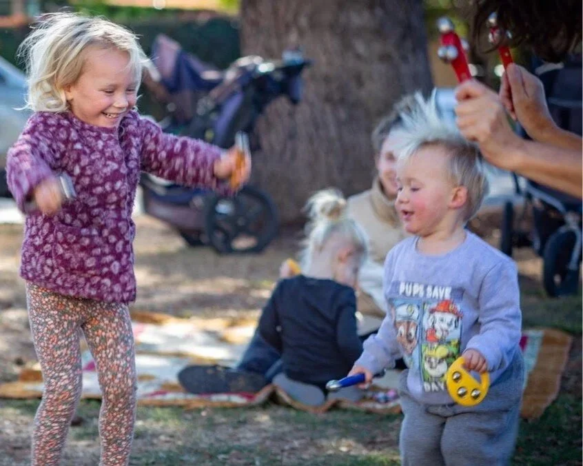 Children jumping with joy and enjoying shakers with their mother at Kathy's Music & Movement Family Music Time Class