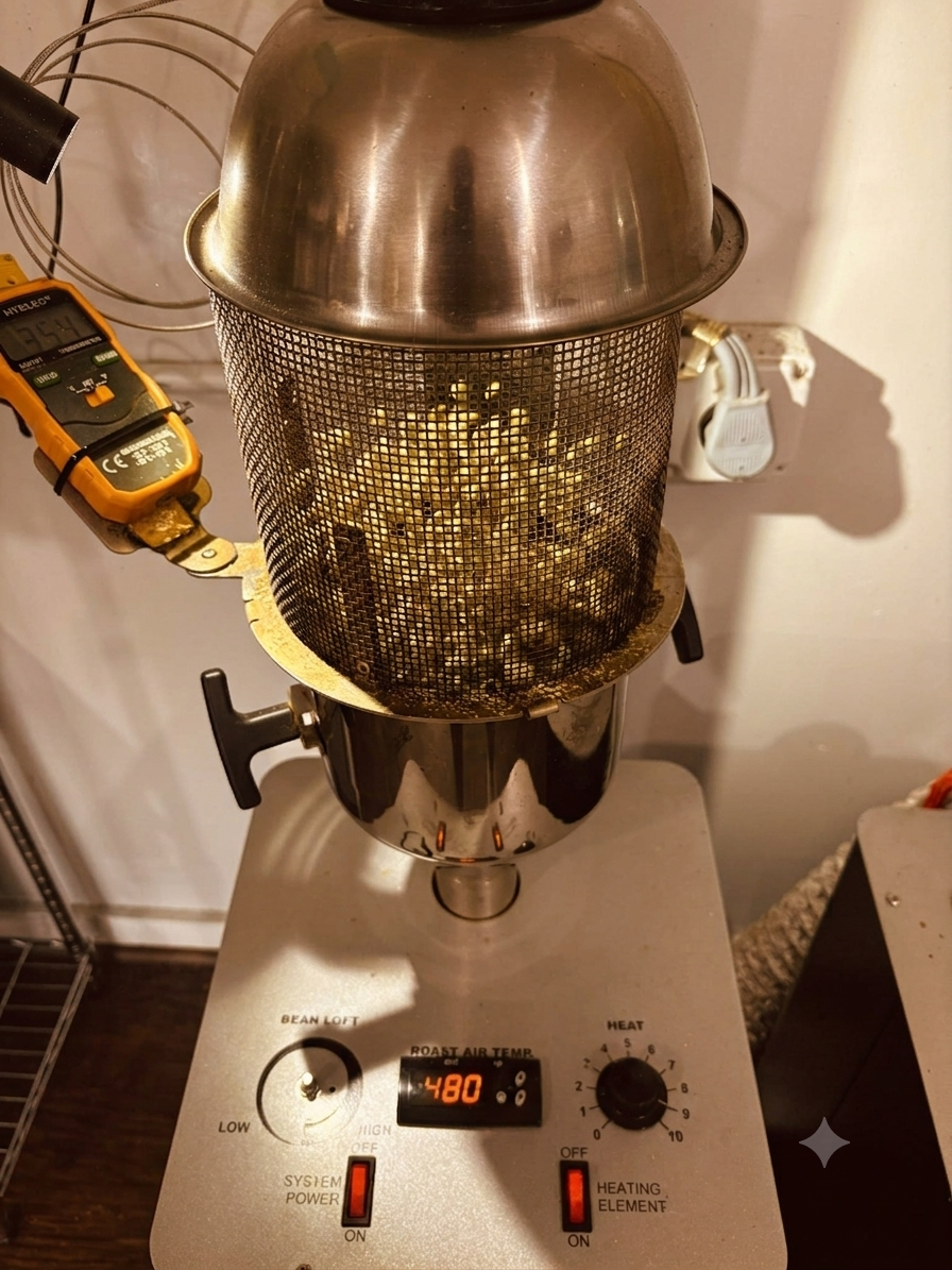 A stovetop with a metal pot, a mesh strainer filled with roasted coffee beans, a digital thermometer, and a warming lid. The control panel shows a roast air temperature of 480°F.