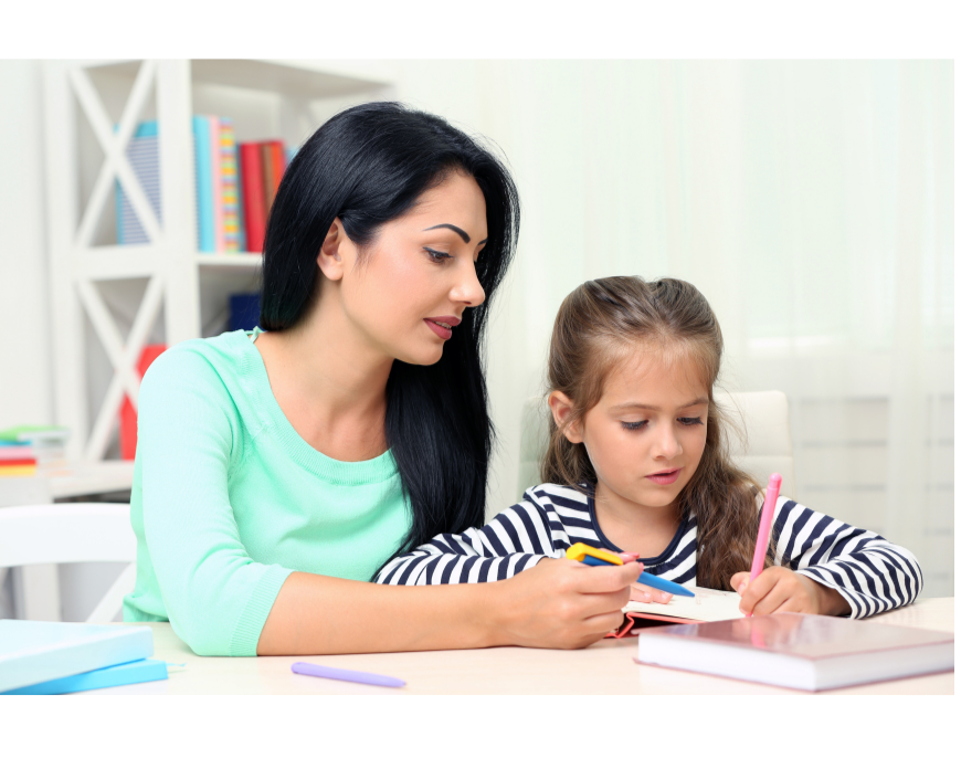 A woman helping a young girl with homework at a desk in a bright room.