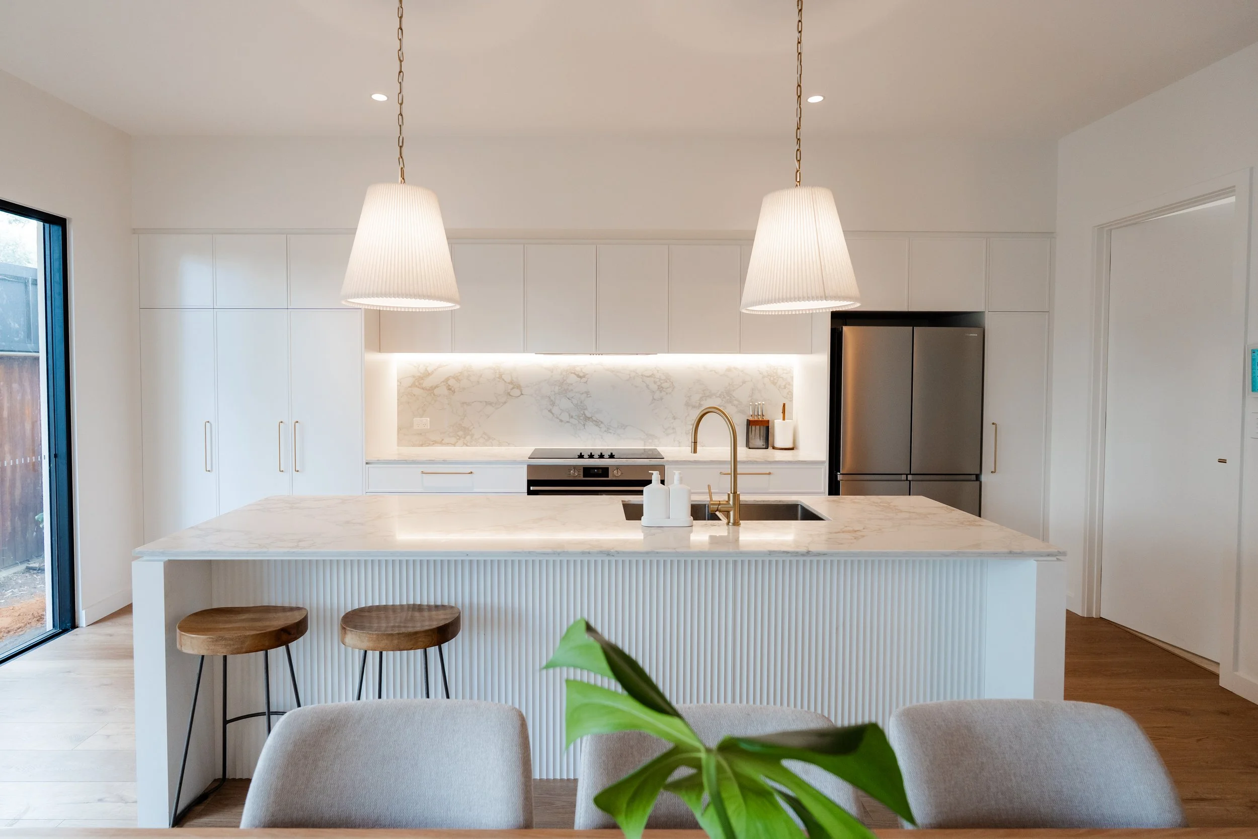 Folded Polytec Thermolaminated end panels in Classic White, Feature Cove panelling, Lavistone Eleganto Gold Benchtops and Splashbacks & Lux Handles Curved Brass  