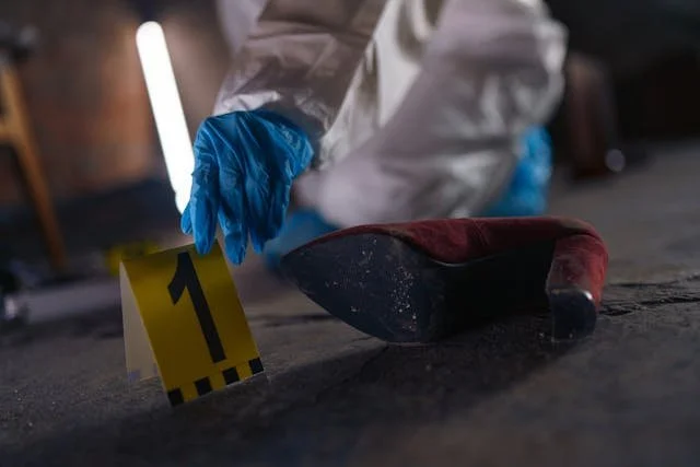 A photograph of a crime scene investigator places a "1" sign next to a shoe