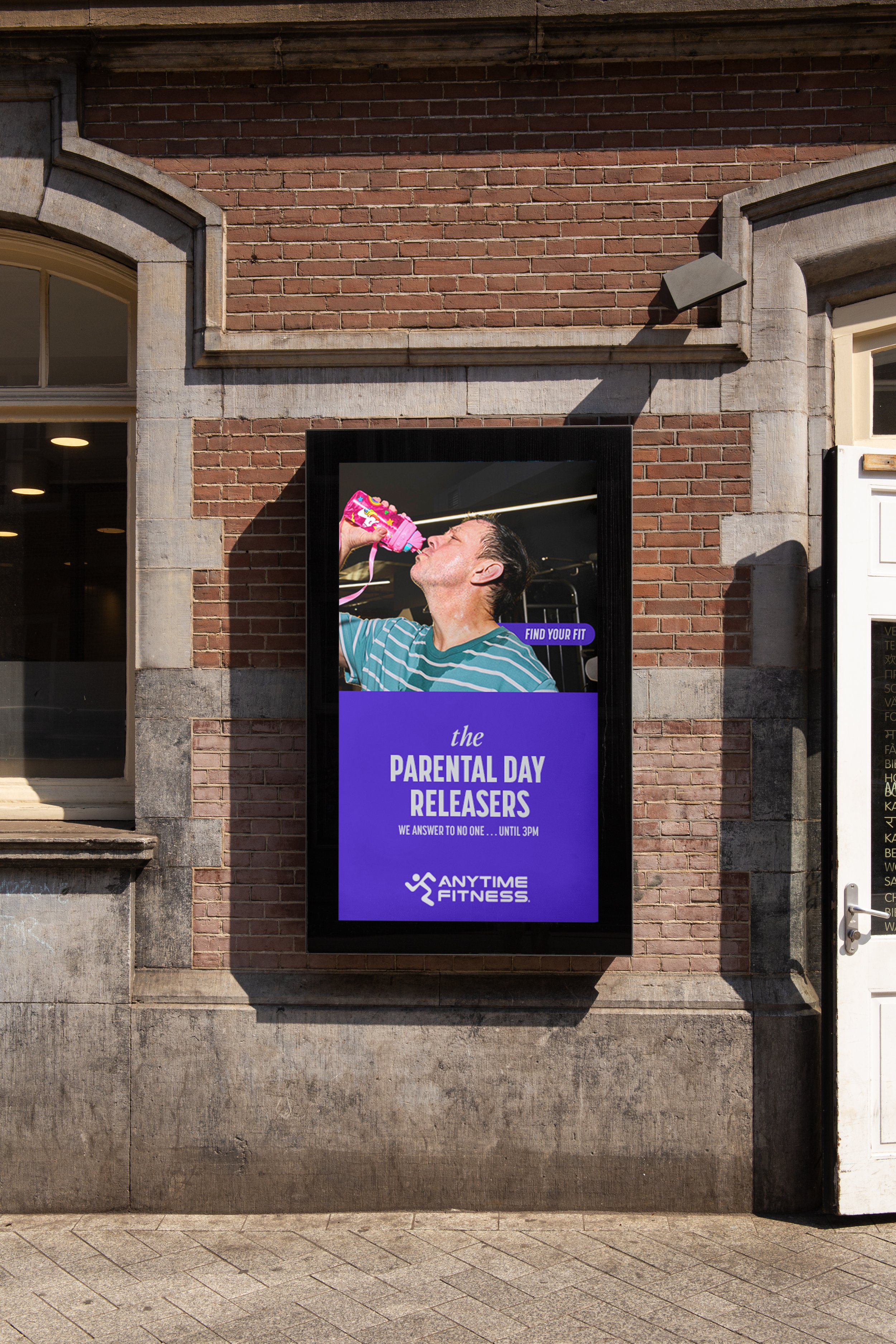 Digital billboard advertising a parody event called "the parental day releasers" at Anytime Fitness, featuring a man drinking from a pink bottle.