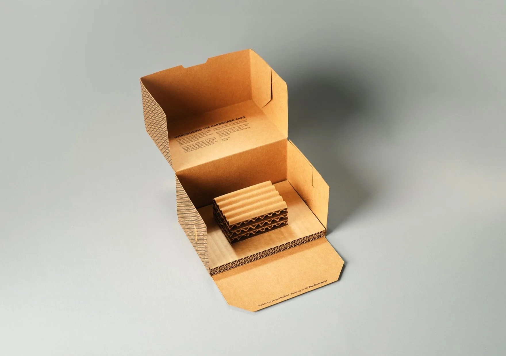 Open cardboard box with cardboard pieces inside, placed on a light gray surface