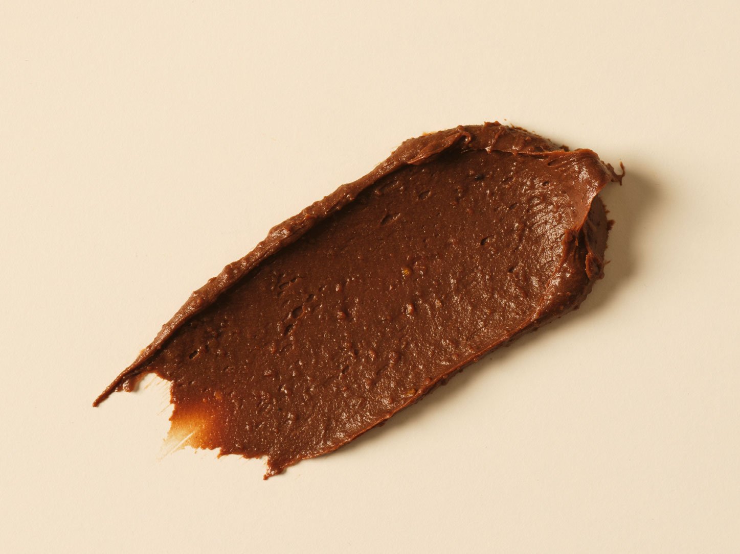 A smear of brown, smooth-textured chocolate spread on a white surface.