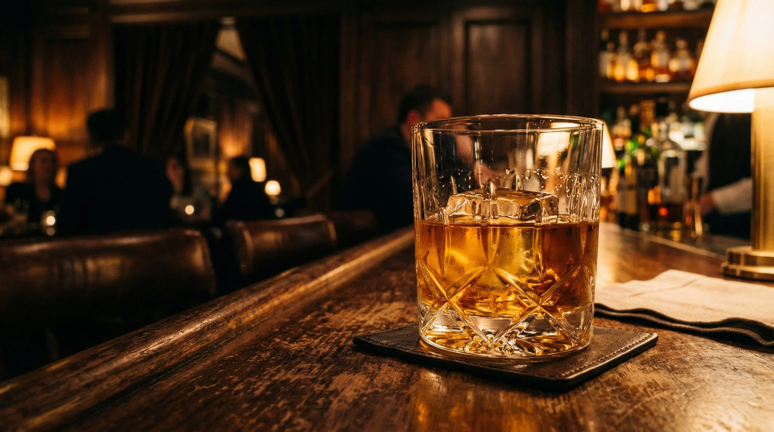 Glass of whisky on bar table with warm lighting
