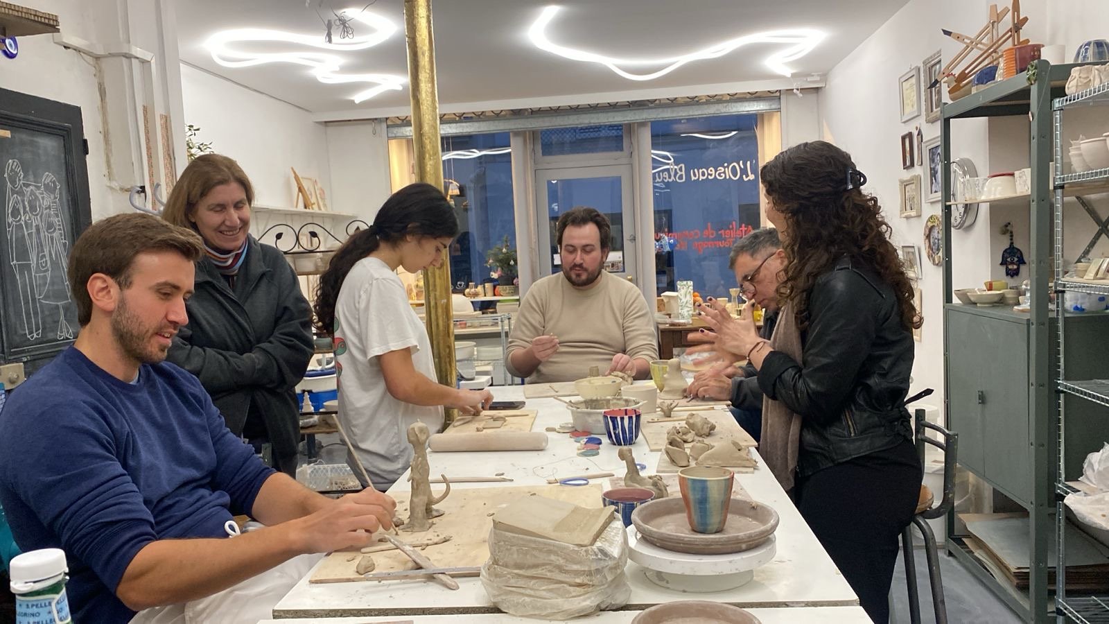 Deux mains, une propre et une sale, façonnent de l'argile sur une surface en bois.