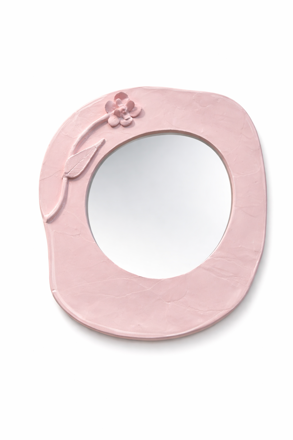 Miroir rond avec cadre en plastique rose pastel, orné d'une décorative fleur et feuille en relief.