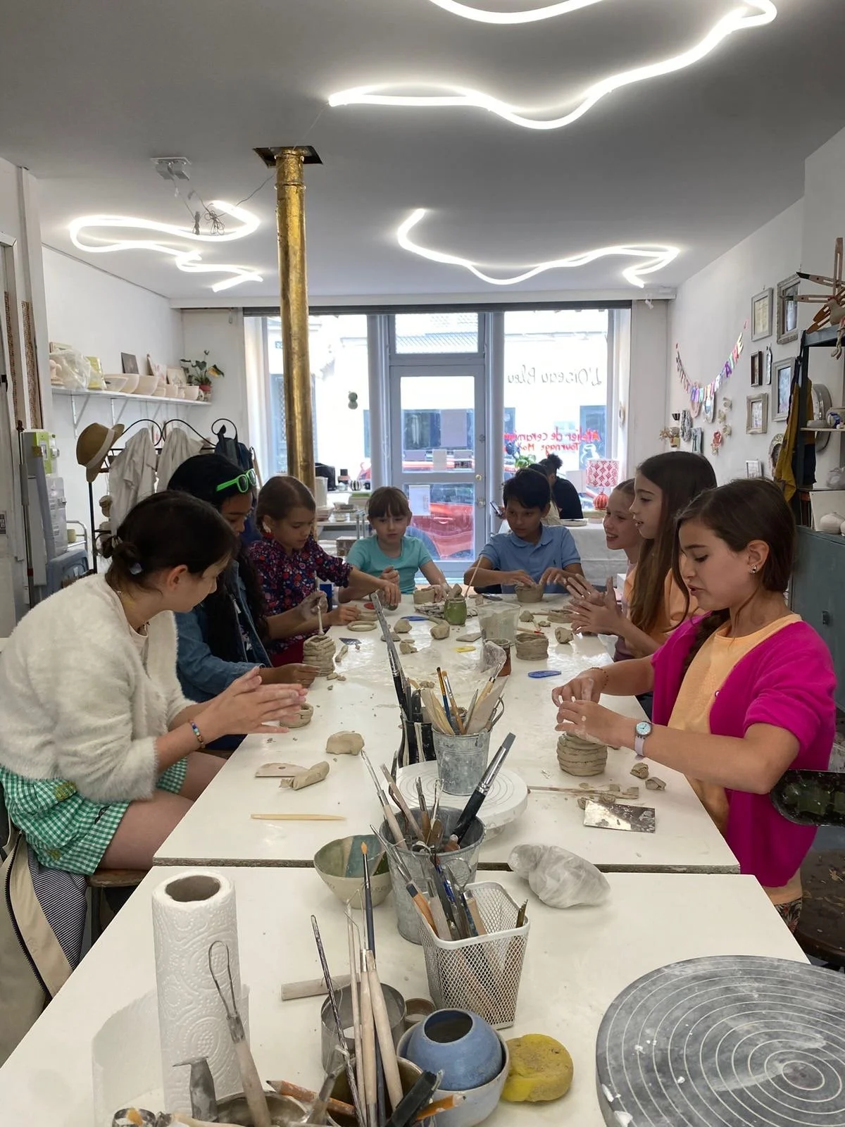 Une personne en train de peindre ses doigts avec de la peinture bleue, la main est couverte de peinture et le fond est flou avec d'autres couleurs.