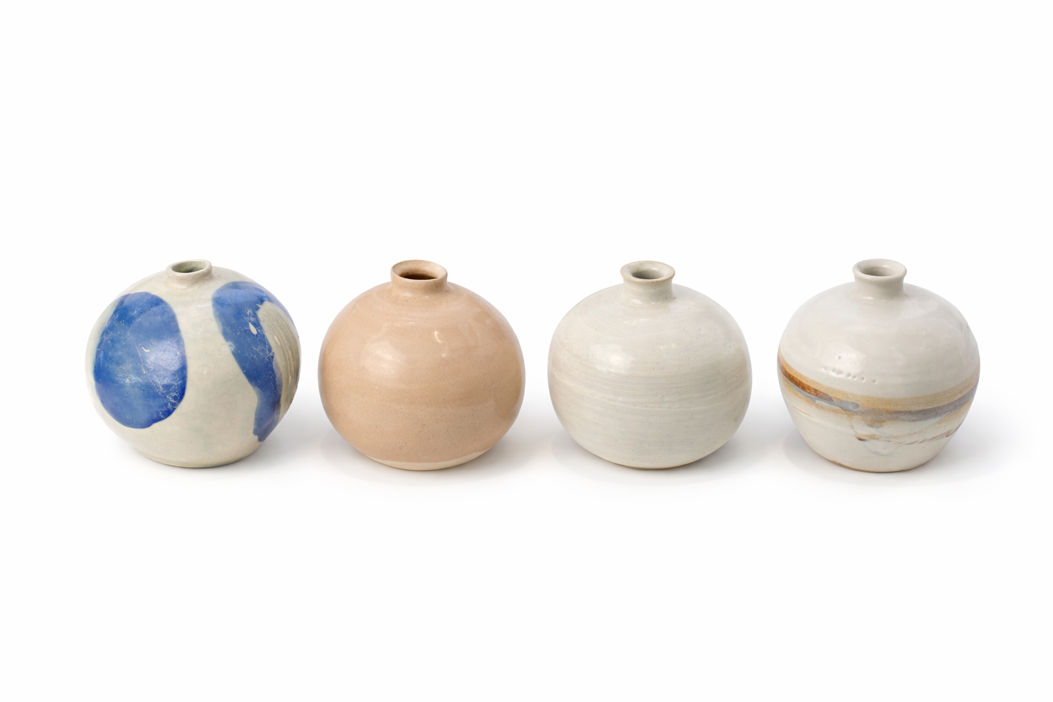 Quatre petits vases en céramique de différentes couleurs et motifs, disposés en ligne sur fond blanc.