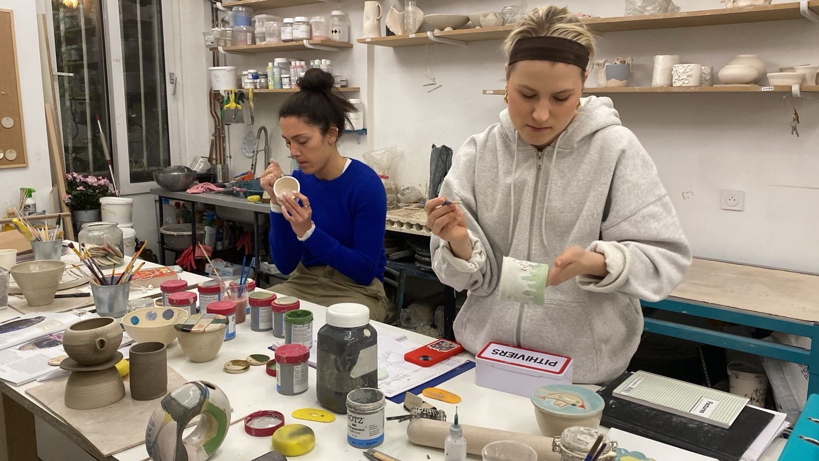 Quatre jeunes femmes discutent et utilisent des appareils électroniques dans un café.